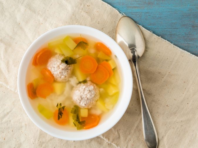 bowl of soup, a cup of broth and vegetables, meatballs made of turkey and chicken, top view
