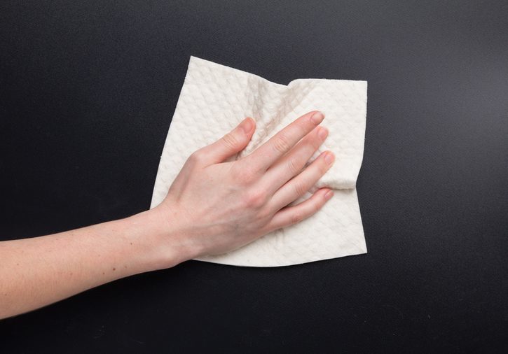 Hand hold dry cleaning cloth. Woman's hand clean kitchen black table