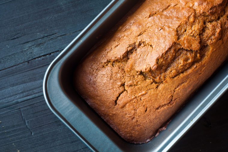 Freshly baked pumpkin bread cake in a baking tin. Perfect in Autumn Fall and served on a black wooden table.