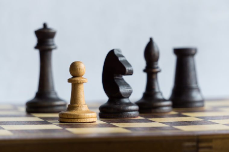 Black chess pieces pursuing a white pawn