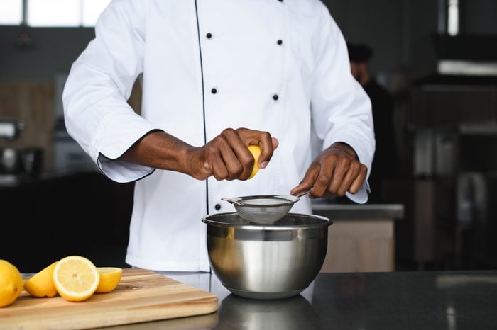 cropped image of african american chef squeezing lemons at restaurant kitchen