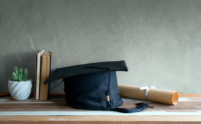 graduation cap, hat with degree paper on wood table graduation concept.