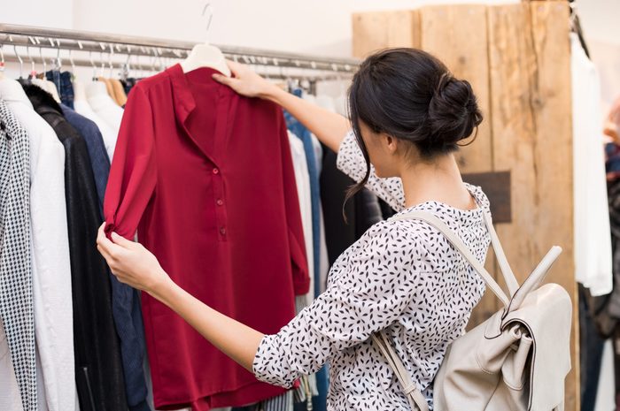 Woman choosing blouse from new collection of clothes in a boutique