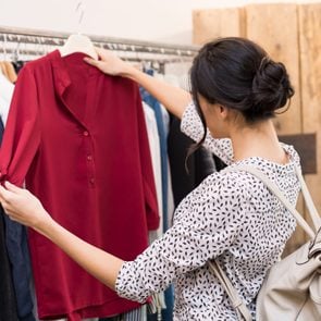 Woman choosing blouse from new collection of clothes in a boutique
