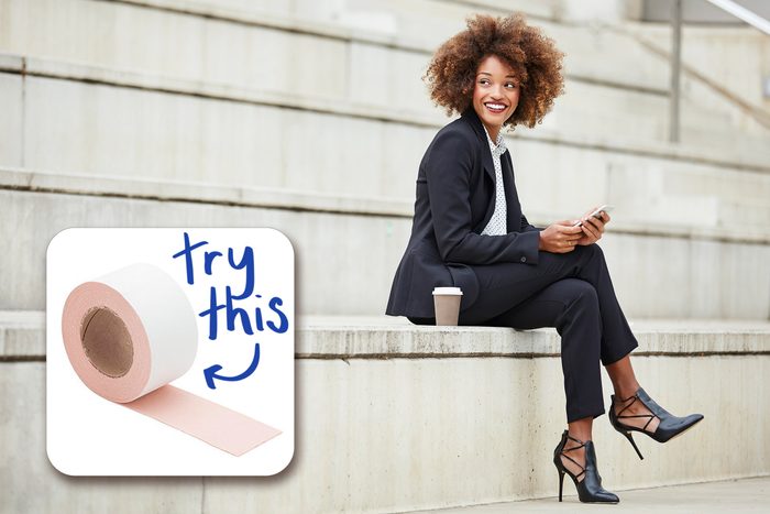 yound business woman sitting on steps outdoors with coffee cup and cellphone. professional attire and high heels.