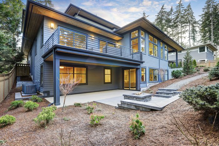 Luxury new construction home with blue wood siding. Patio area with fire pit on the first floor and deck with outdoor furniture on the second. Northwest, USA