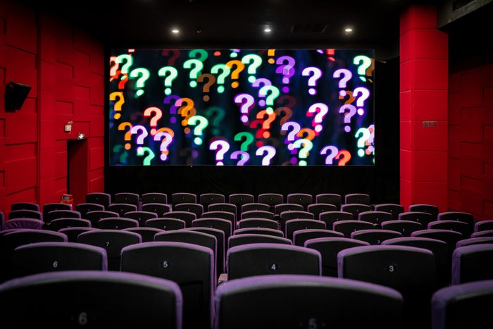 empty movie theatre with a screen of question marks