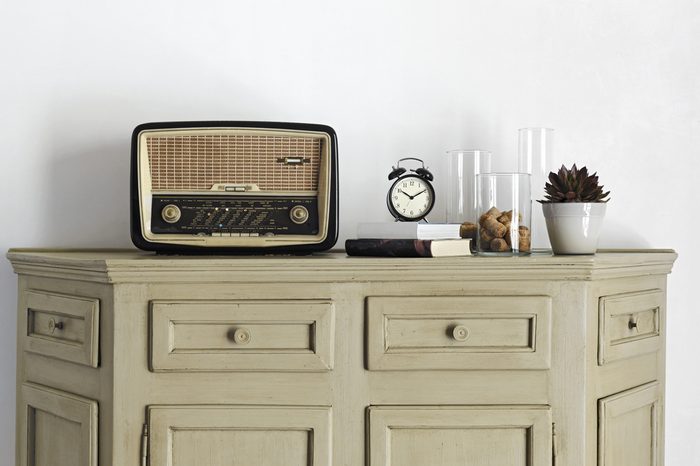 old radio and alarm-clock on the book on old sideboard