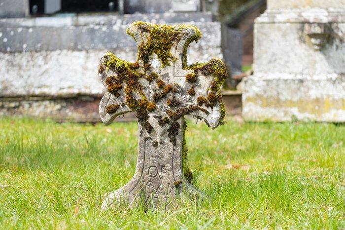 Ancient stone cross with moss on graveyard in Girsterklaus, Luxembourg.