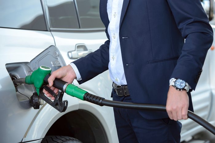 Young businessman refueling car tank at fuel station