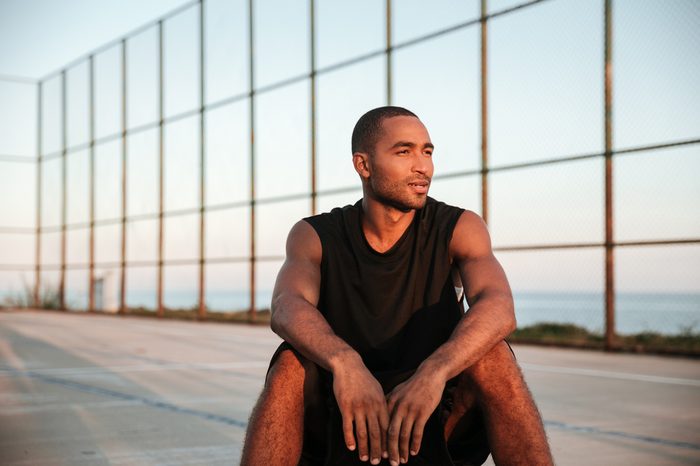 Portrait of a young basketball player sitting and resting after the game at the playground