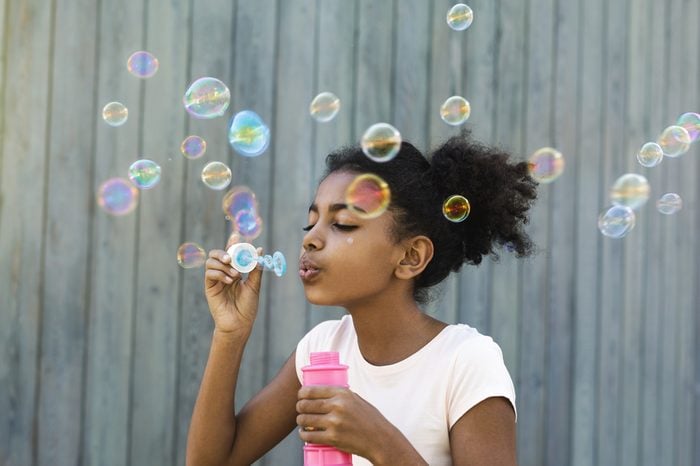 Portrait of cute girl blowing bubbles outdoors