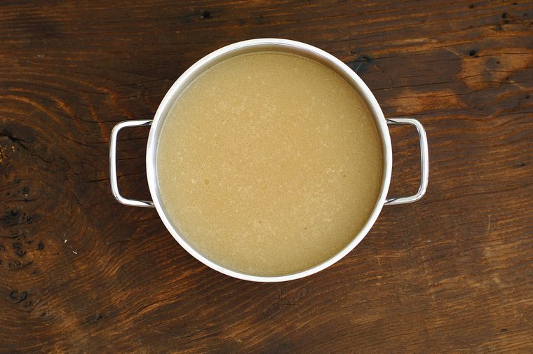 Fresh bone broth in a pot, on a rustic table, drained, top view, home made delicious bone stock