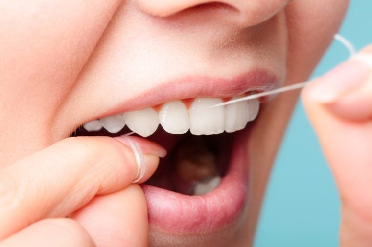 Гигиена полости рта и уход за здоровьем.  Улыбающиеся женщины используют зубную нить для белых здоровых зубов.