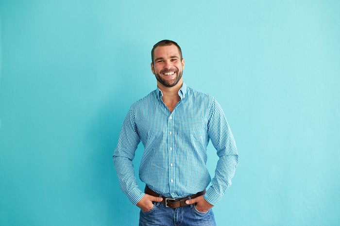 Smiling man standing in front of turquoise wall