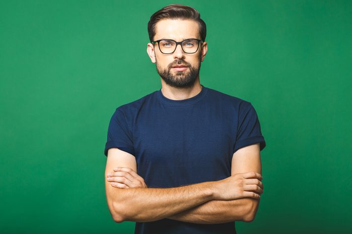 A portrait of young handsome man in casual isolated on green background with glasses.