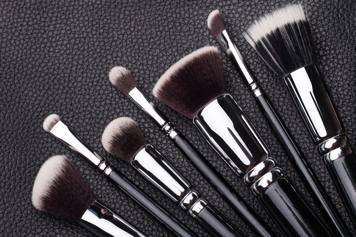 Set of professional makeup brushes over black leather background