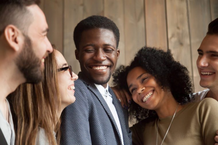 Happy diverse black and white people group with smiling faces bonding together, cheerful african and caucasian young multi ethnic friends having fun laughing embracing, multiracial friendship concept