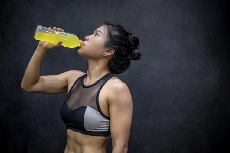 Young Asian athlete woman drinking sport drink or energy drink after exercise in fitness gym, healthy lifestyle concepts