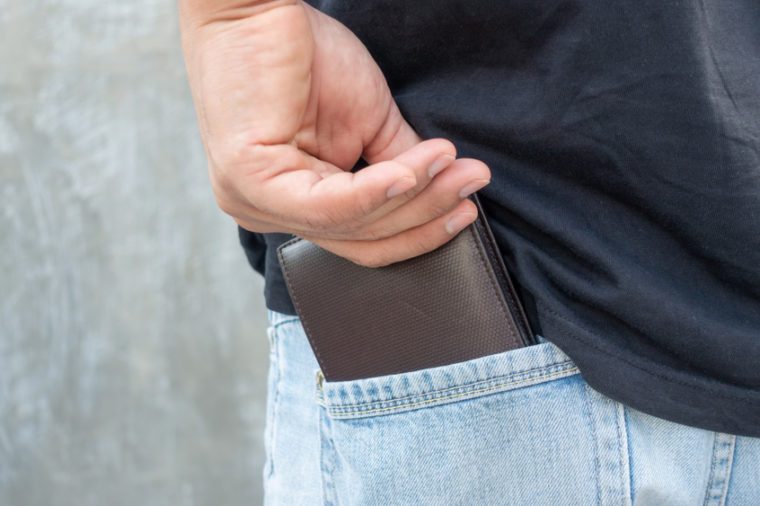 Men hold a brown wallet from a jeans pocket.