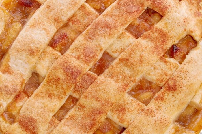 homemade whole apple pie with a lattice pastry crust covered with cinnamon and granulated sugar. The background is a black place mat.