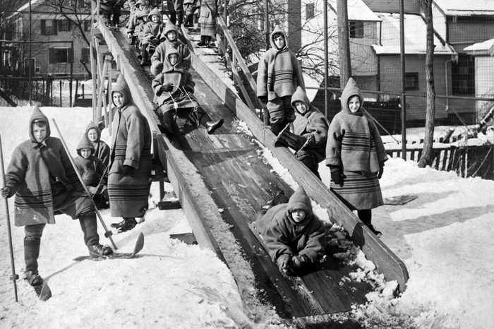 Children sliding on a wooden chute at an open-air school