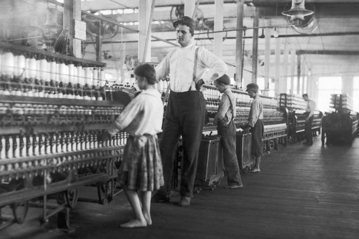 A young spinner being watched by the overseer at Yazoo City Yarn Mills.