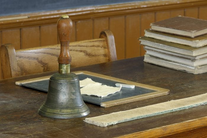 school teacher's desk with books, slate, chalk, bell and strap
