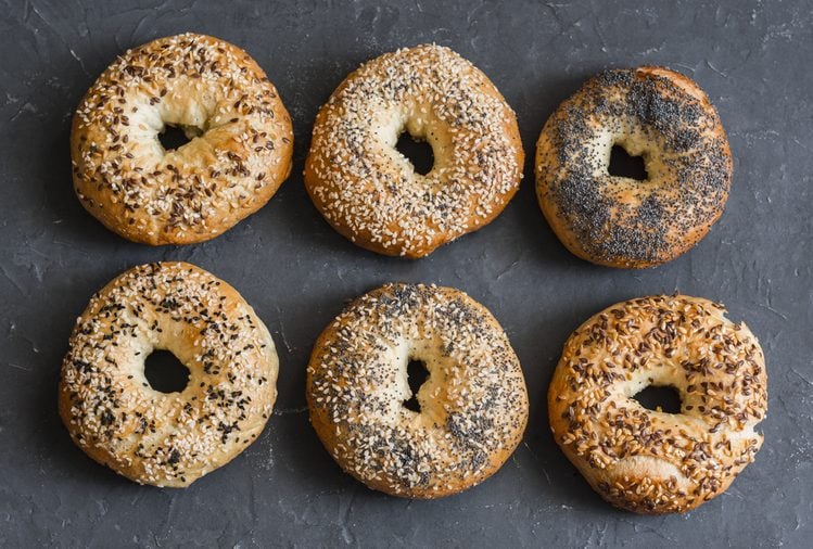 Homemade bagels with a variety of seeds on a gray background, top view. Food background.