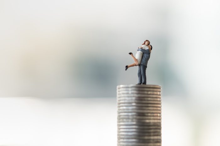 Saving, Couple in love and Family Concept. Man and woman in love miniature figure standing on top of stack of coins