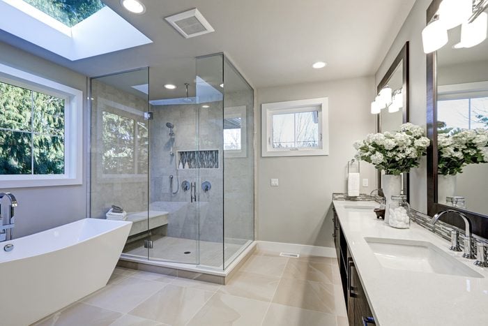 Spacious bathroom in gray tones with heated floors, freestanding tub, walk-in shower, double sink vanity and skylights. Northwest, USA