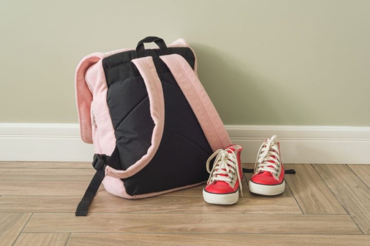 School backpack and sneakers on the floor in a home interior