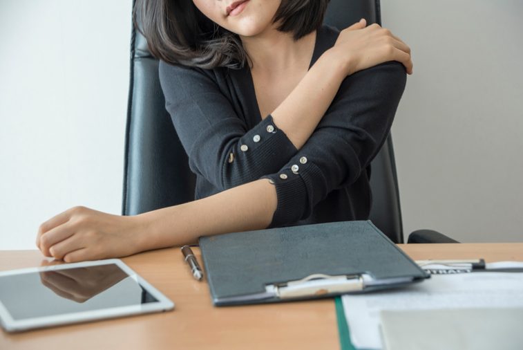 woman at laptop with shoulder pain