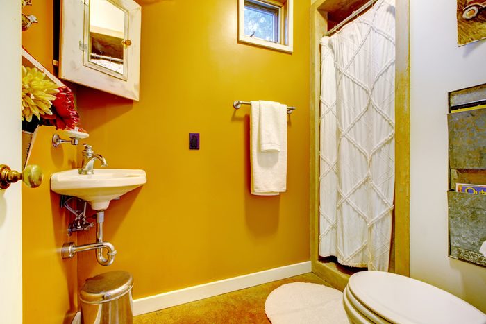 Bright mustard yellow interior of unique vintage style bathroom