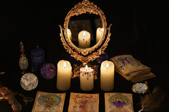 Fortune telling ritual with the Tarot cards, mirror, crystals and vintage objects. Halloween concept, black magic still life or witch spell with occult and esoteric symbols, divination rite.