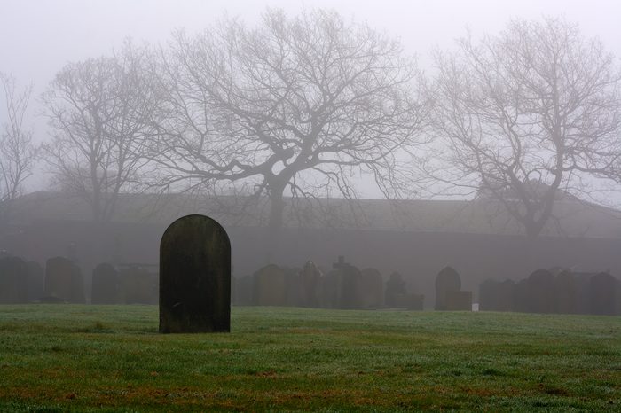 Single gravestone in a spooky graveyard on a foggy day