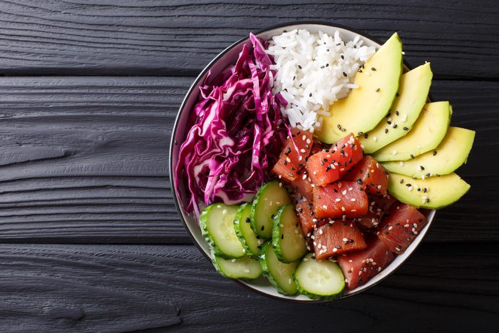 Raw Organic Ahi Tuna Poke Bowl with Rice and Veggies close-up on the table. Top view from above horizontal