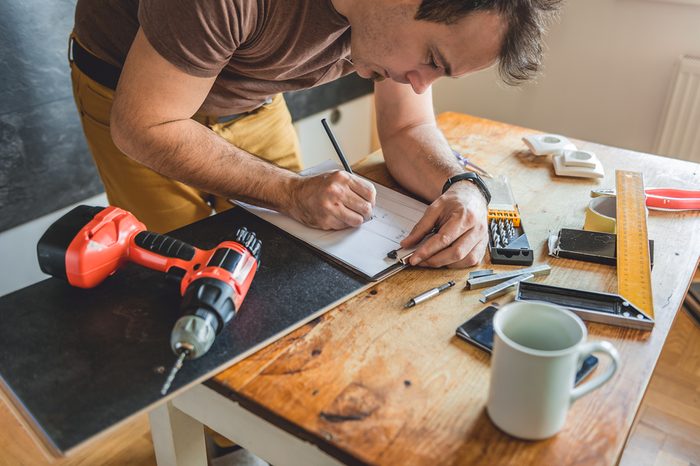 Man making draft plan using pencil on the table with tools
