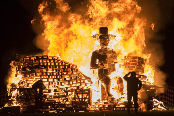 Man standing in front of a Guy Fawkes bonfire during the 5th of November at Lindifield bonfire night, West Sussex, England