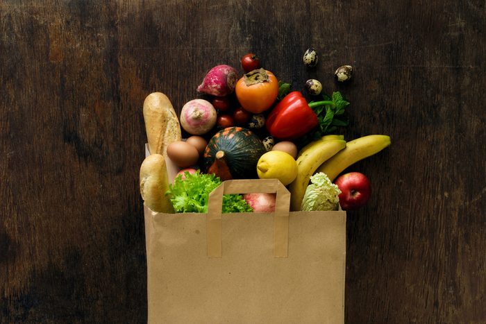 Paper bag of different health food on dark wooden background. Top view. Flat lay