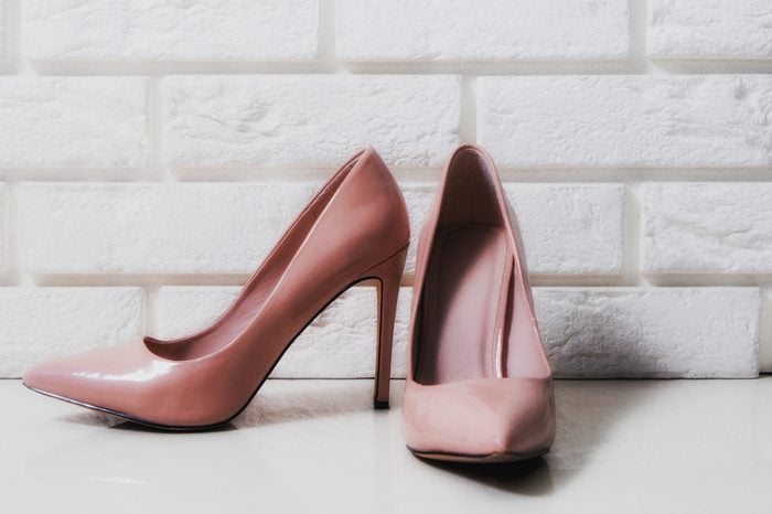High heels. Beige high heels with a mascara on a white, brick background. The concept of fashion, modernity. Female high heels lie on white floor, two high heels.