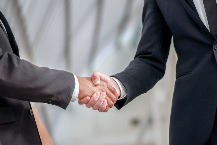 Welcoming business partners Handshake. Two successful businessman sitting at the table looking at each other shaking hands