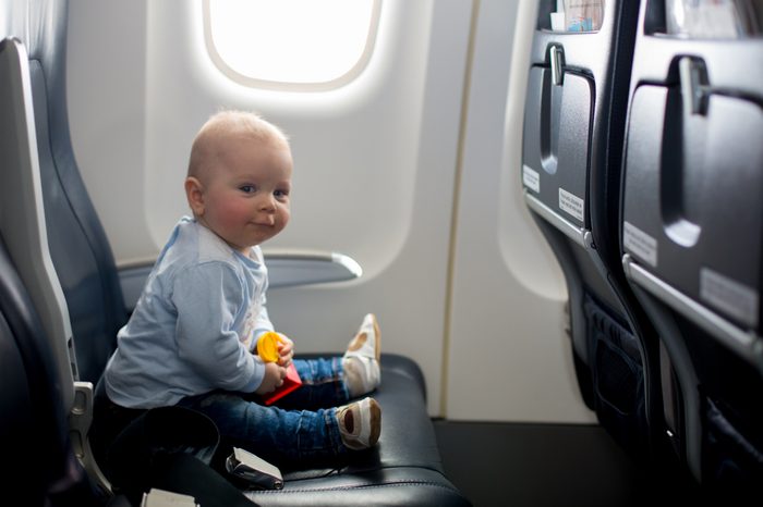 Cute baby boy, playing with toys on board of aircraft, traveling on vacation with parents and siblings