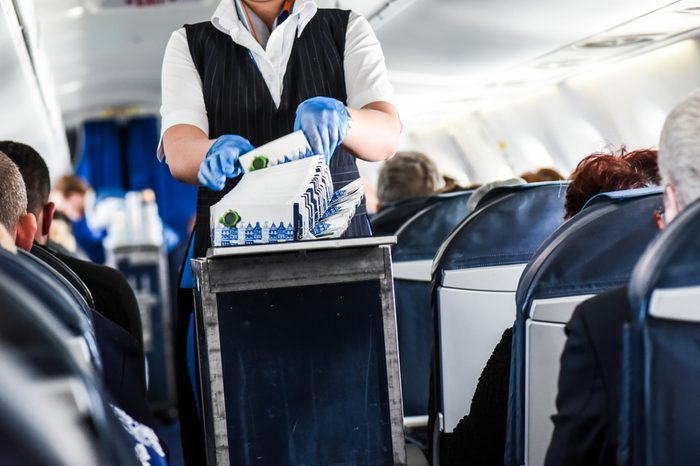 Stewardess cleaning garbage in airplane after lunch.