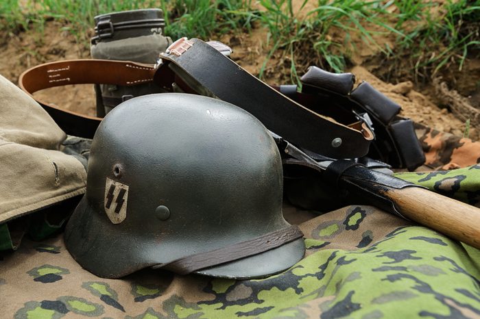 German helmet and outfit from the time of the Second World War lie in a trench on a camouflage raincoat