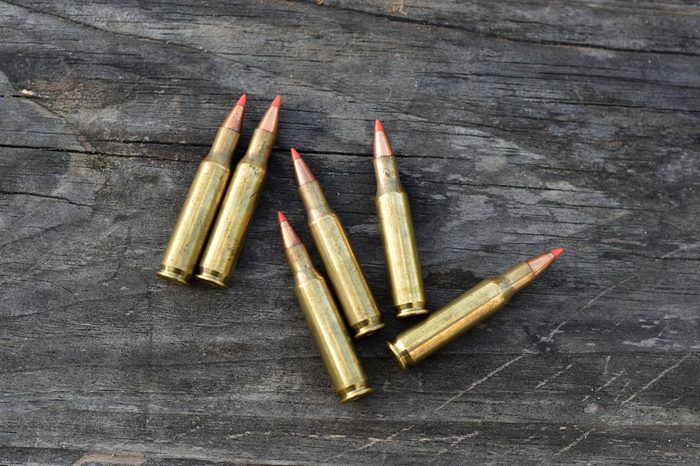 six of 223 bullet lay on wooden backgound