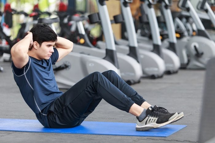 Asian sport man doing sit-ups on the floor in gym. man exercising in fitness gym for good health. Athletic young man exercising equipment at gym, workout in fitness center.