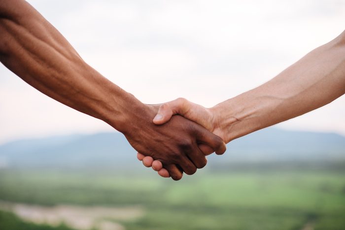 Close-up of mixed race couple holding hands on the green mountain background