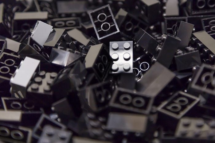 Pile of black color building blocks with selective focus and highlight on one particular block using available light.