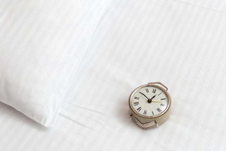 Vintage alarm clock on a bed in a hotel room. Wake up call concept